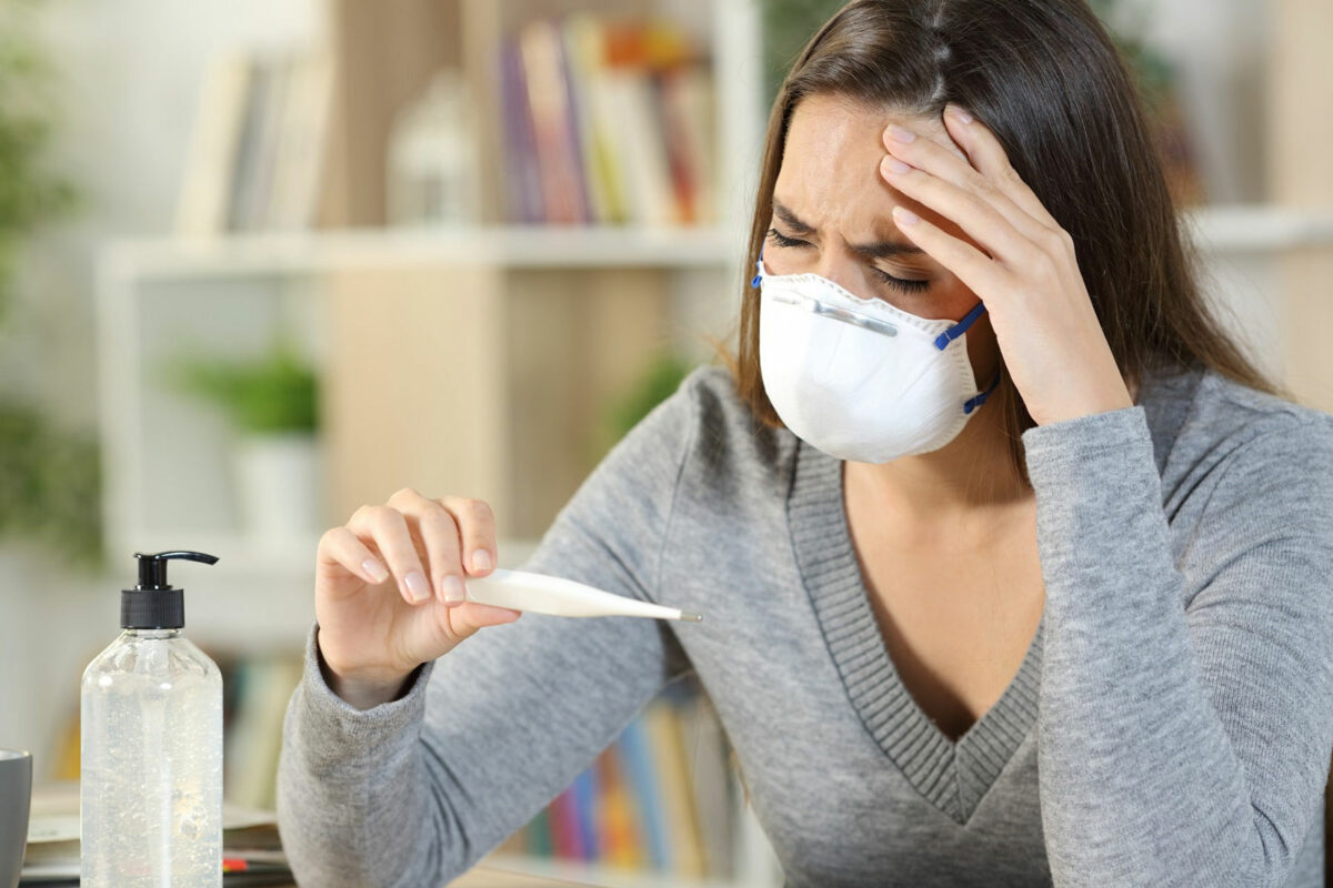 Woman looks at temperature with mask on